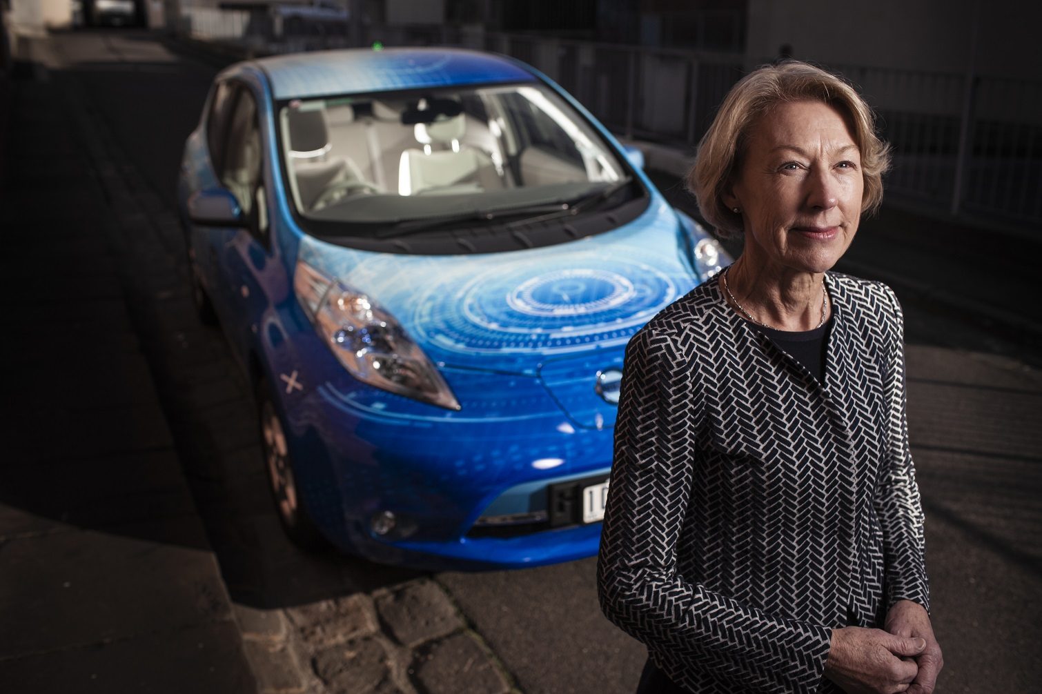 Professor Doreen Thomas stands in front of an electric car.