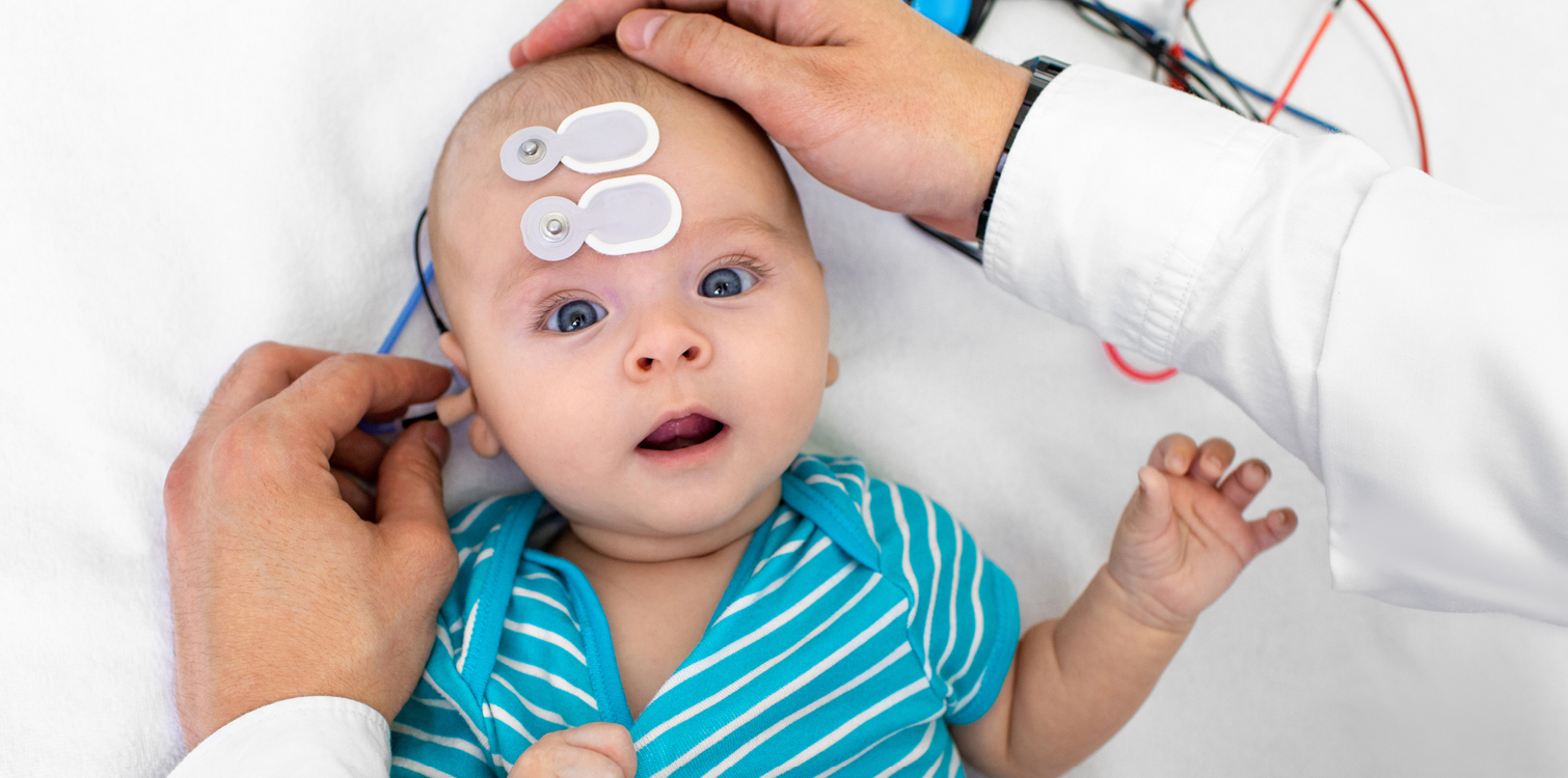 Baby having hearing screening with special electrodes on his head and ear