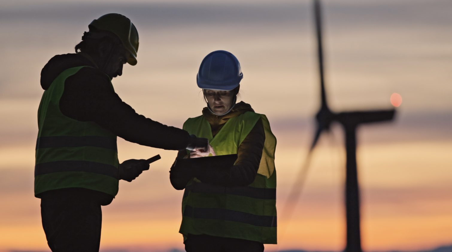 Alternative energy concepts. Maintenance engineers supervising the condition of the power equipment in a wind turbines power station with digital tablet. Teamwork.